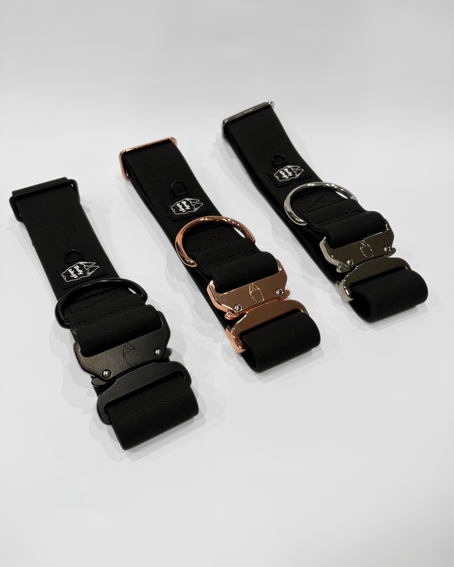Black 2-inch waterproof PVC dog collars with black, silver, and rose gold hardware, displayed at an angle with visible buckles on a light gray background.