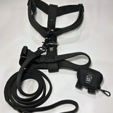 Black Y-strap dog harness, matching nylon leash, and portable poop bag dispenser set displayed on a white background.