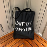 Bully Wags tote bag with the phrase "Happy Dog, Happy Life" displayed on a wooden bench
